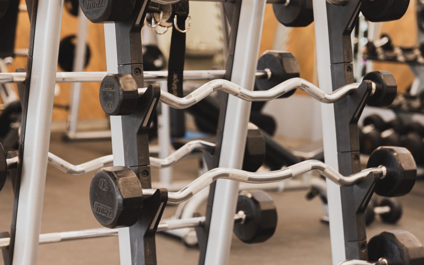 SZ-Stangen und Kurzhanteln auf Ständern im Fitnesscenter